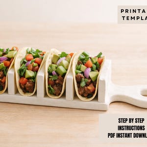May include: Four fully loaded tacos in a white ceramic taco holder. The tacos are filled with ground meat, diced avocado, tomatoes, red onions, and coriander. The image includes the text "PRINTABLE TEMPLATE" and "STEP BY STEP INSTRUCTIONS PDF INSTANT DOWNLOAD."