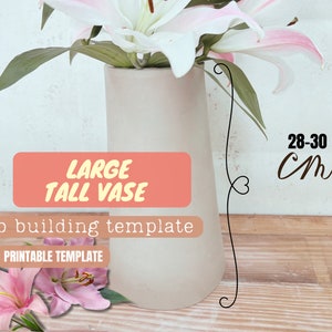 Puede incluir: Un jarrón alto y claro que contiene lirios blancos y rosas. El jarrón mide aproximadamente 28-30 cm de alto. El texto en la imagen dice "LARGE TALL VASE" y "Slab building template".