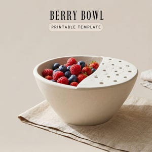 May include: A beige berry bowl filled with fresh raspberries and blueberries. The bowl features a semi-circular lid with circular drainage holes. The text BERRY BOWL PRINTABLE TEMPLATE is displayed above the bowl in a clean, dark font.