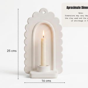 A white ceramic candle holder with a lit candle inside, along with dimensions provided in centimeters.