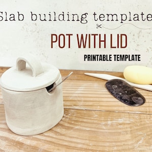 Puede incluir: Una olla de cerámica blanca con tapa y asa. La olla está sobre una superficie de madera. El texto "Slab building template POT WITH LID PRINTABLE TEMPLATE" es visible sobre la olla.