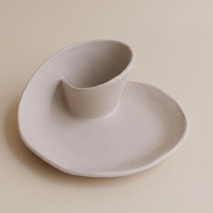 A white ceramic plate with a unique, curved design sits on a light-colored surface.