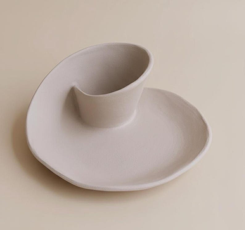 A white ceramic plate with a unique, curved design sits on a light-colored surface.