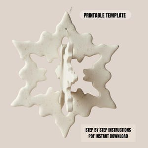 May include: A white, snowflake-shaped ornament with a textured surface. The ornament has a three-dimensional design, with a smaller snowflake inside the larger one. The text "PRINTABLE TEMPLATE" and "STEP BY STEP INSTRUCTIONS PDF INSTANT DOWNLOAD" are visible.