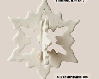 Puede incluir: Adorno blanco en forma de copo de nieve con una superficie texturizada. El adorno tiene un diseño tridimensional, con un copo de nieve más pequeño dentro del más grande. El texto "PRINTABLE TEMPLATE" y "STEP BY STEP INSTRUCTIONS PDF INSTANT DOWNLOAD" son visibles.
