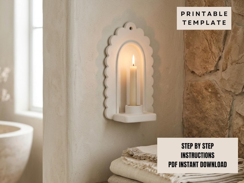 a white scalloped-edge wall-mounted candle holder with a lit candle inside, placed on a shelf next to a stack of towels.