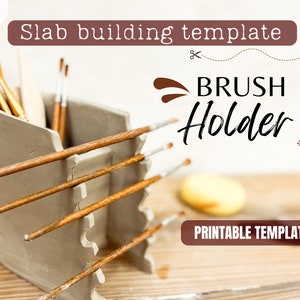 Puede incluir: Un portacepillos de cerámica gris hecho a mano con un diseño único. El soporte tiene ranuras para cepillos y un compartimento para herramientas. El texto "Brush Holder" y "Printable Template" son visibles. El soporte está lleno de varios pinceles.