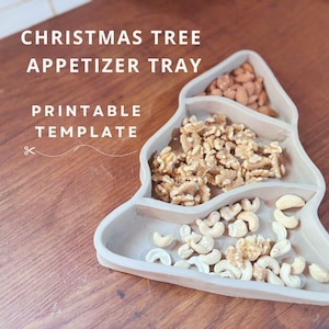 Peut inclure: Un plateau d'apéritif en forme de sapin de Noël gris avec trois sections remplies d'amandes, de noix et de noix de cajou. Le plateau est sur une surface en bois. Le texte "CHRISTMAS TREE APPETIZER TRAY PRINTABLE TEMPLATE" est au-dessus du plateau.