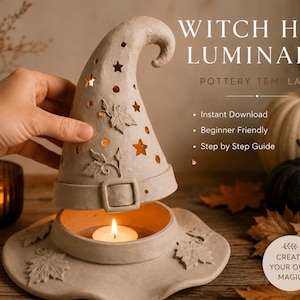 A hand is holding a white ceramic witch's hat with a lit candle inside, surrounded by autumn leaves and pumpkins on a wooden surface.
