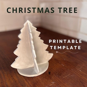 Könnte beinhalten: Hellfarbene, zweiteilige Weihnachtsbaumdekoration. Der Text "CHRISTMAS TREE" steht oben und "PRINTABLE TEMPLATE" rechts. Der Baum steht auf einer Holzoberfläche.