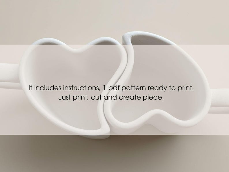 May include: Two white heart-shaped objects are connected, with the text "It includes instructions, 1 pdf pattern ready to print. Just print, cut and create piece." The objects are on a light background.
