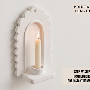 a white candle holder with a lit candle inside, mounted on a wall.