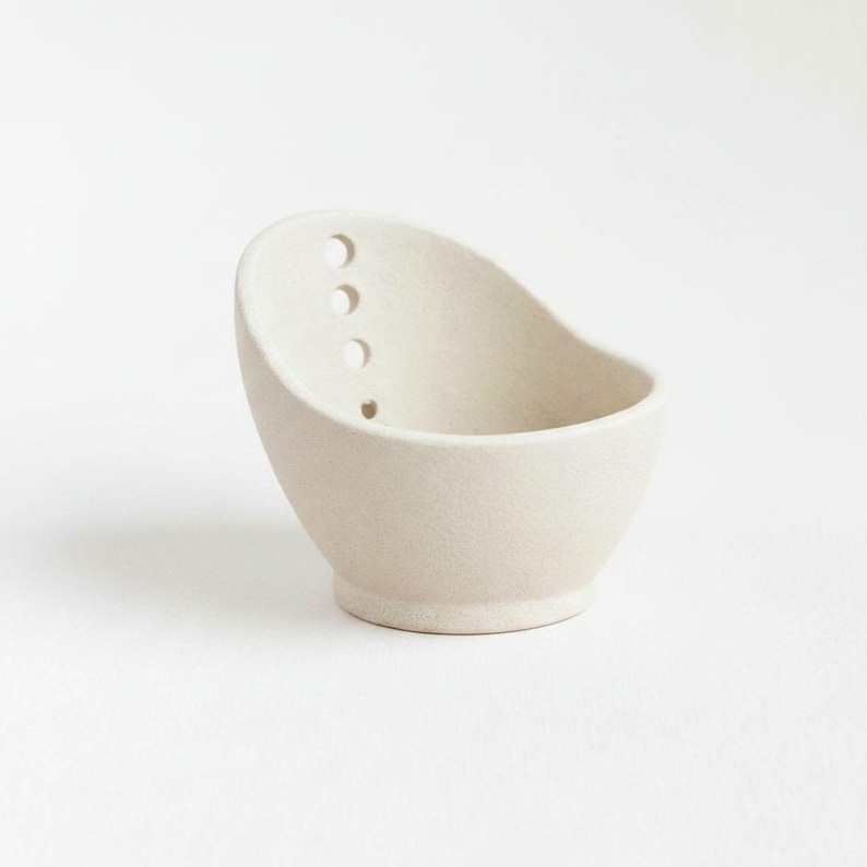 A simple, white ceramic bowl with three holes on the side.