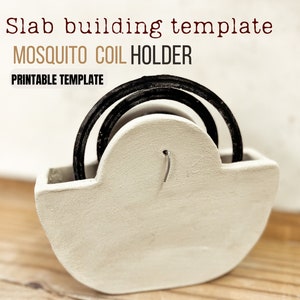 May include: White ceramic mosquito coil holder with a rounded shape. The holder has a small hole in the top for hanging. A black mosquito coil is placed inside the holder.