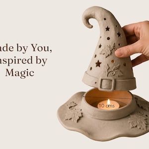 A hand is holding a small candle holder in the shape of a wizard's hat, with a lit candle inside.