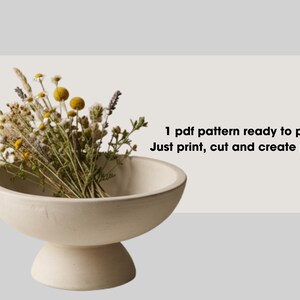 a white ceramic bowl filled with a variety of dried flowers, including yellow and purple blooms, placed on a white surface.