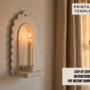 a white candle holder mounted on a wall, with a lit candle inside.