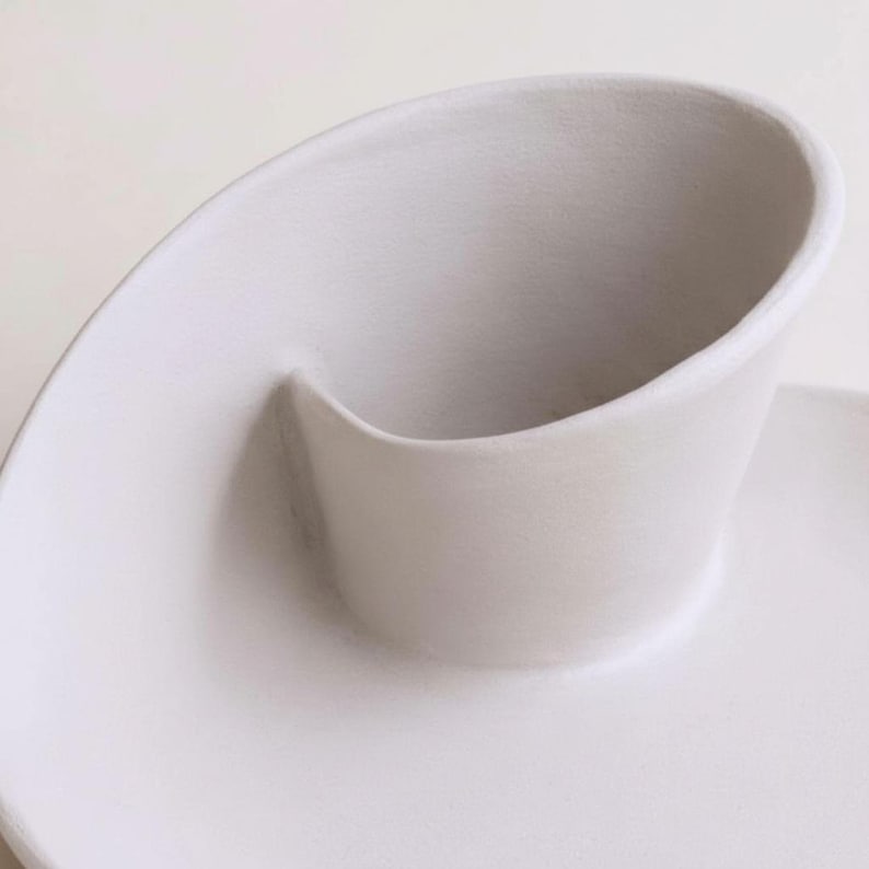 A close-up view of a white ceramic cup or bowl with a curved shape.