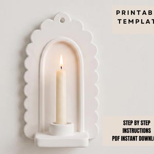 a white candle holder with a lit candle inside, set against a plain white background.
