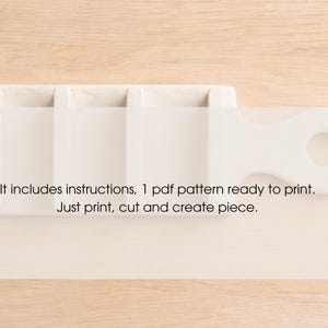 May include: A white, rectangular craft tool with a handle and a circular opening. The tool has multiple compartments. Text on the image reads: "It includes instructions, 1 pdf pattern ready to print. Just print, cut and create piece."