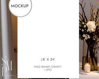 May include: A white rectangular sign on a black easel, with the text "MOCKUP" in a circle at the top. The sign is 18" x 24" and includes the text "PSD SMART OBJECT + JPG". A floral arrangement and candle are in the background.