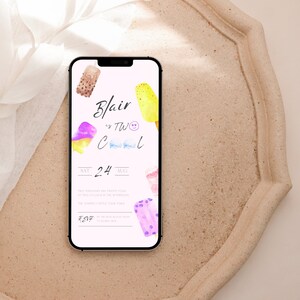 Puede incluir: Un smartphone muestra una invitación rosa con ilustraciones de paletas de acuarela. El texto dice "Blair is TW Cool" con la fecha "24 de agosto" e información de RSVP. El teléfono está sobre una bandeja decorativa beige.