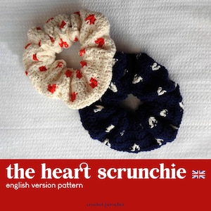 Peut inclure: Deux chouchous en crochet, l'un avec des cœurs rouges sur fond crème et l'autre avec des cœurs blancs sur fond bleu marine. Le texte "the heart scrunchie" est écrit en blanc sur fond rouge.