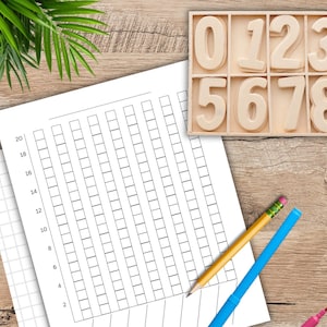 May include: A wooden tray with the numbers 0-9, a grid chart, and a pencil and markers on a wooden surface. The chart has a grid of squares with numbers along the side. The pencil is yellow with a pink eraser. The markers are pink and blue.