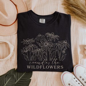 May include: Black t-shirt with a white outline of wildflowers and the text "consider the wildflowers".
