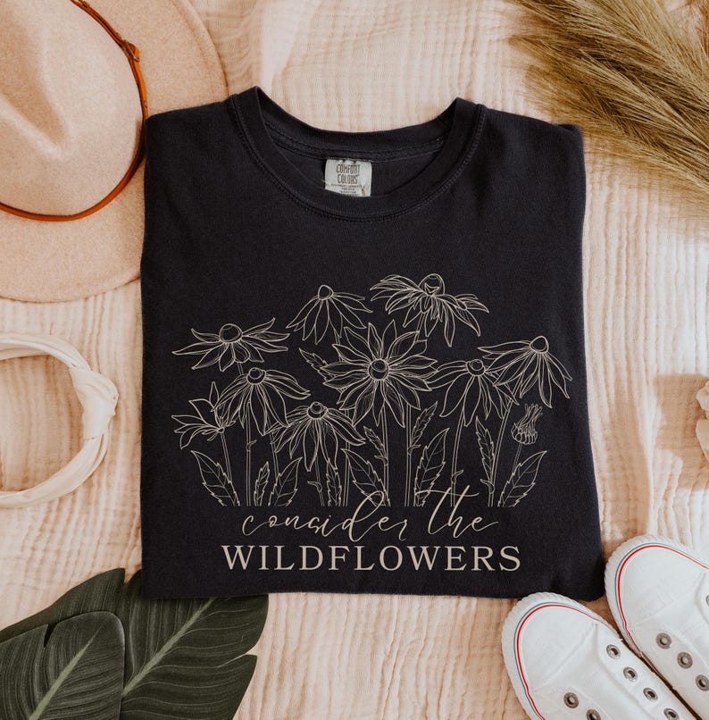 May include: Black t-shirt with a white outline of wildflowers and the text "consider the wildflowers".