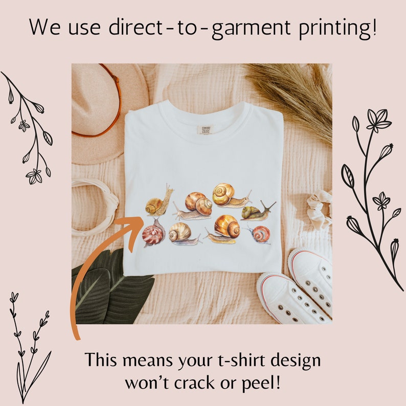 May include: White t-shirt with a design of multiple snails in shades of brown and beige. The text "We use direct-to-garment printing! This means your t-shirt design won't crack or peel!" is visible on the image.