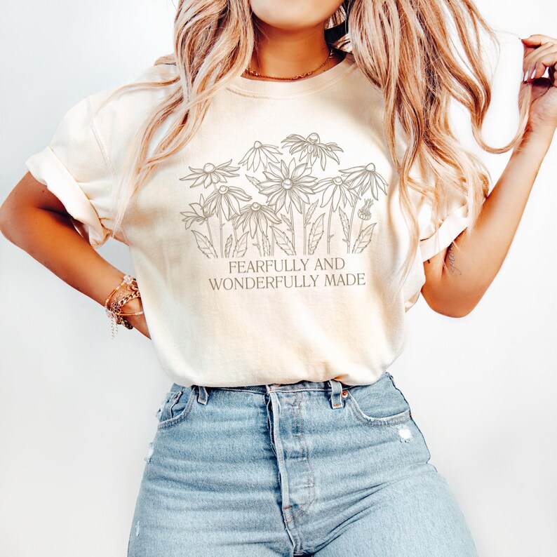 May include: A white t-shirt with a floral design and the text "Fearfully and Wonderfully Made".