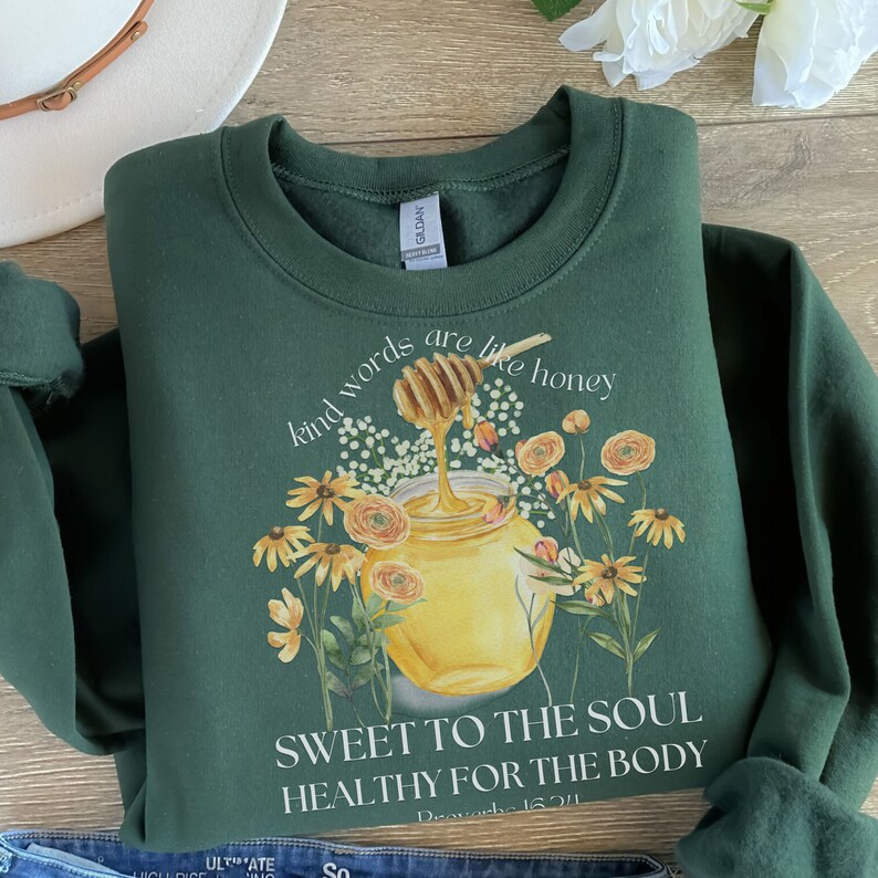 Puede incluir: Sudadera verde con un dise&ntilde;o de tarro de miel y flores. El texto dice "Kind words are like honey, Sweet to the soul, Healthy for the body, Proverbs 16:24".