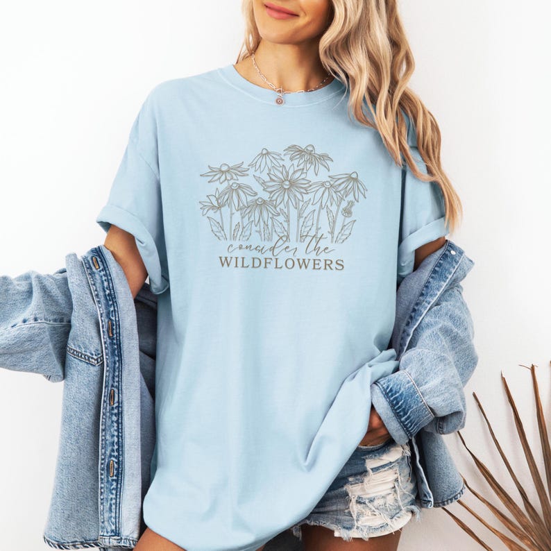 May include: A light blue t-shirt with a graphic of wildflowers and the text "consider the wildflowers".