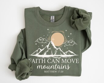 May include: A green sweatshirt with a white graphic of a mountain range with a sun and stars. The text "Faith can move mountains" and "Matthew 17:20" is printed below the graphic.