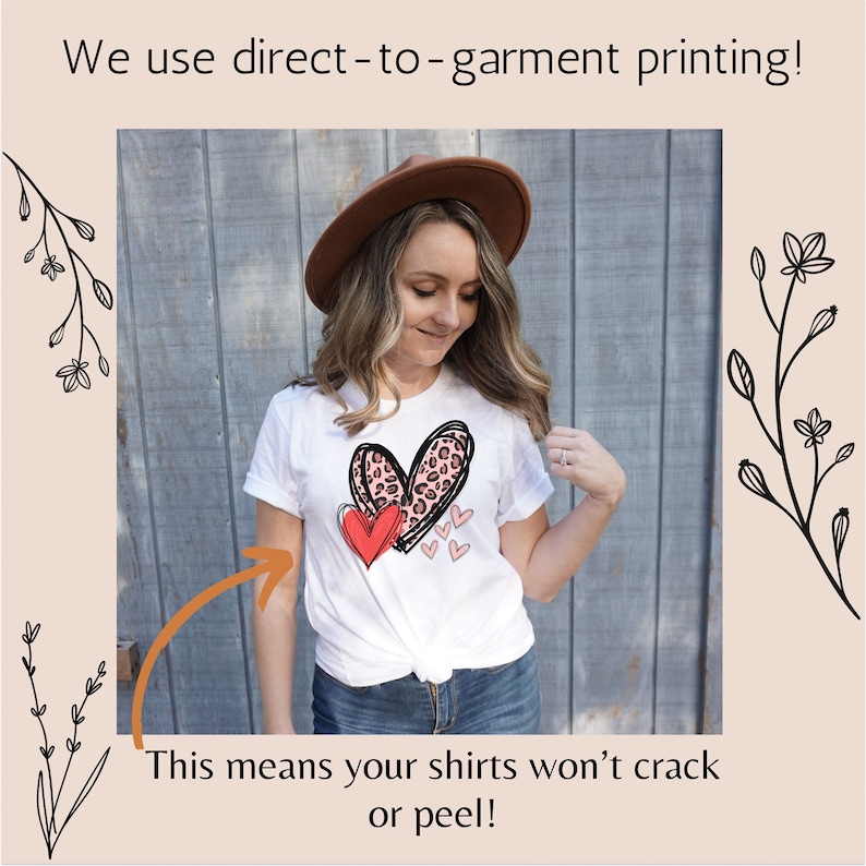 May include: A white t-shirt with a pink and red heart design printed on the front. The text "We use direct-to-garment printing!" is at the top of the image. The text "This means your shirts won't crack or peel!" is at the bottom of the image.