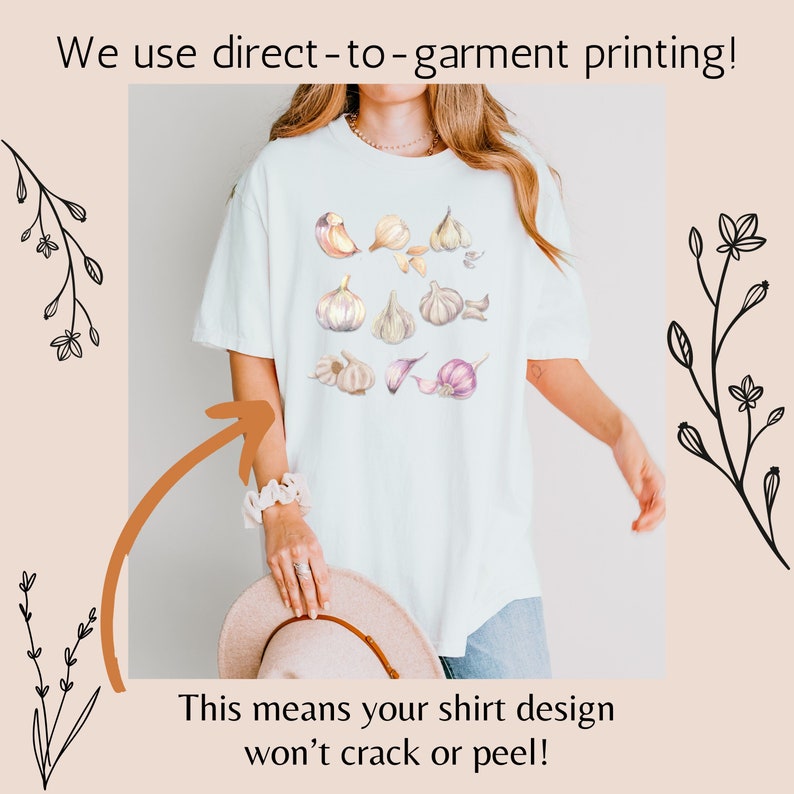 May include: White t-shirt with a watercolor design of garlic cloves. The text "We use direct-to-garment printing! This means your shirt design won't crack or peel!" is printed on the bottom of the image.
