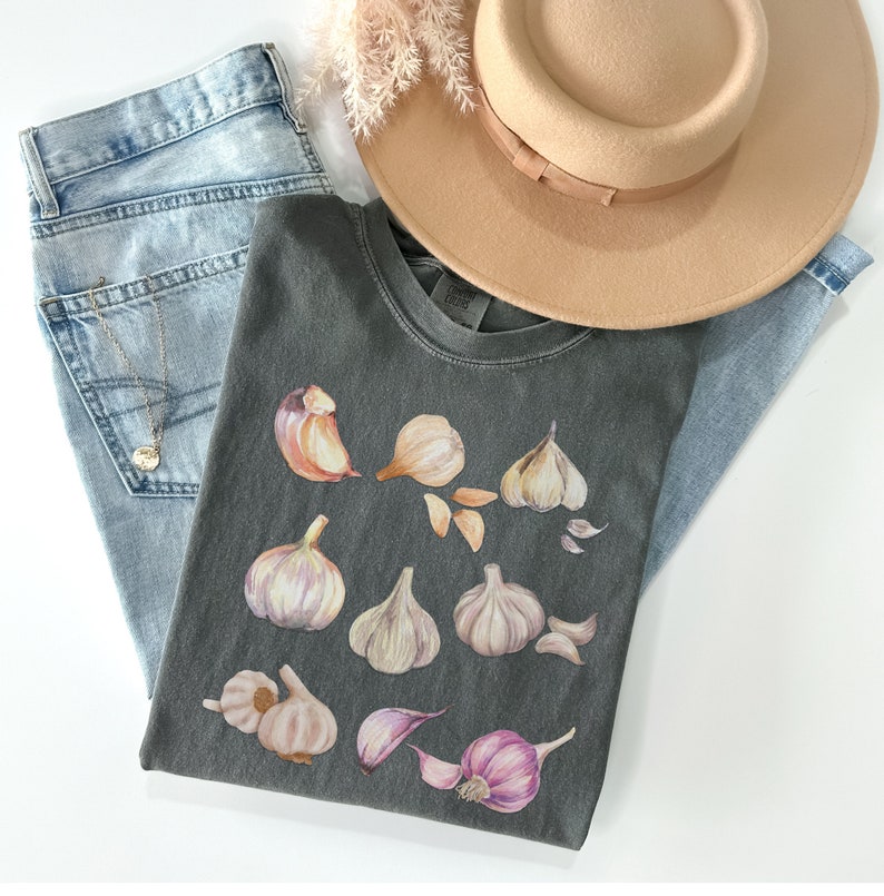 May include: A dark gray t-shirt with a graphic design of multiple garlic cloves in shades of brown, white, and purple.