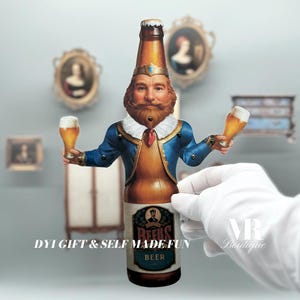 以下が含まれることがあります： ビールグラスを2つ持った王様の段ボール製切り抜き。王様は青と金のローブを着ており、頭に王冠をかぶっている。ビール瓶には「Reus」と「Beer」のラベルが貼られている。「DIY Gift & Self Made Fun」という文字が瓶の下に印刷されている。