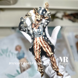May include: A paper Uncle Sam puppet with a red, white, and blue costume, holding a flag and wearing a hat. The puppet is on a white glove. The text "DIY GIFT & SELF MADE FUN" is visible at the bottom of the image.