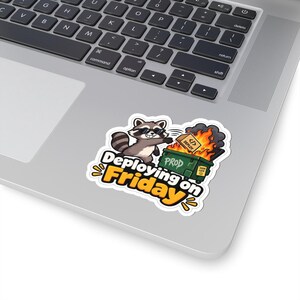 Puede incluir: Una pegatina troquelada con un mapache de dibujos animados con gafas de sol, junto a un contenedor verde etiquetado como PROD envuelto en llamas naranjas. Una caja etiquetada como DEPLOY es arrojada al fuego. El texto dice: Deploying on Friday.