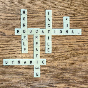 May include: A close-up of a game of Wordle, showing the letters "DYNAMIC", "EDUCATIONAL", "CREATE", "TACTILE", and "FUZZLE" spelled out with letter tiles.