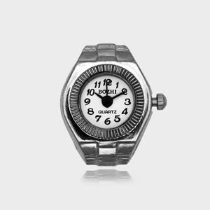May include: A silver ring watch with a white face and black numerals. The watch face displays the brand name "BOZHI" and the word "QUARTZ". The watch has a textured bezel and a crown for setting the time.