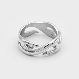 Può includere: Un anello d'argento con un design unico e astratto che presenta un motivo a fiamma vorticoso.