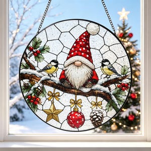May include: A circular stained glass suncatcher featuring a gnome with a red polka-dot hat and white beard sitting on a snowy pine branch. Two small birds, a gold star ornament, a red polka-dot bauble, and a pinecone hang from the branch.