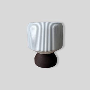 May include: White ceramic planter with a ribbed design and a dark brown base.