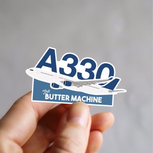 以下が含まれることがあります： 飛行機と「A330 The Butter Machine」というテキストが書かれた青と白のステッカーです。