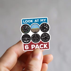 May include: A blue and red sticker with the text "LOOK AT MY 6 PACK" and six black and white aircraft instrument gauges.