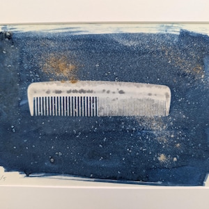 May include: A white plastic comb on a blue background with white speckles. The comb is a common household item used for styling hair.