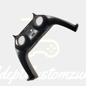 May include: Black plastic part for a video game controller. The part has two circular cutouts and a raised design.